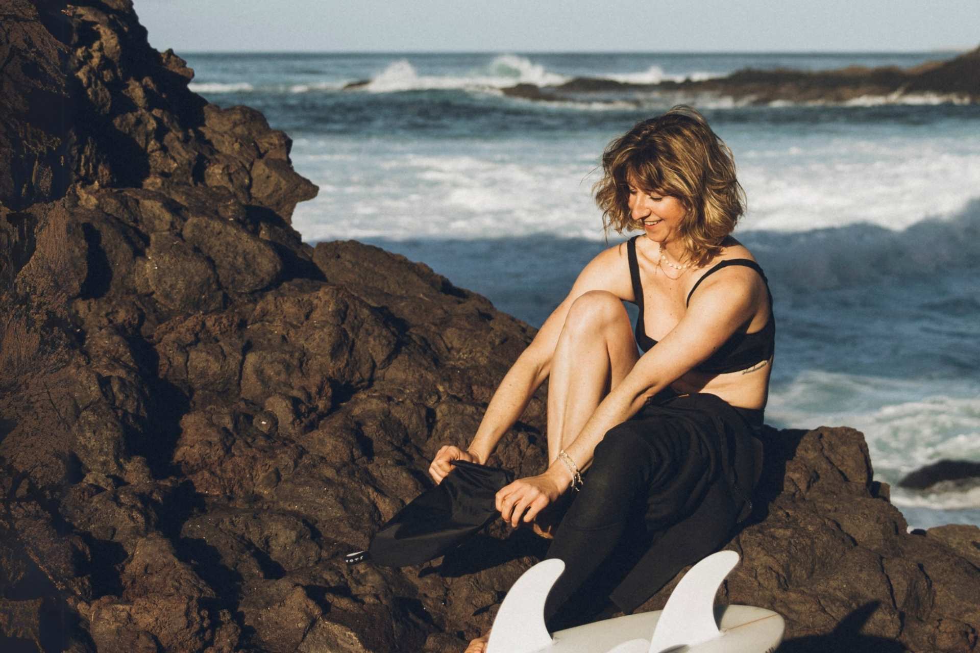 Surferin benutzen Surf Lube Neoprenanzug Anziehhilfe am Meer