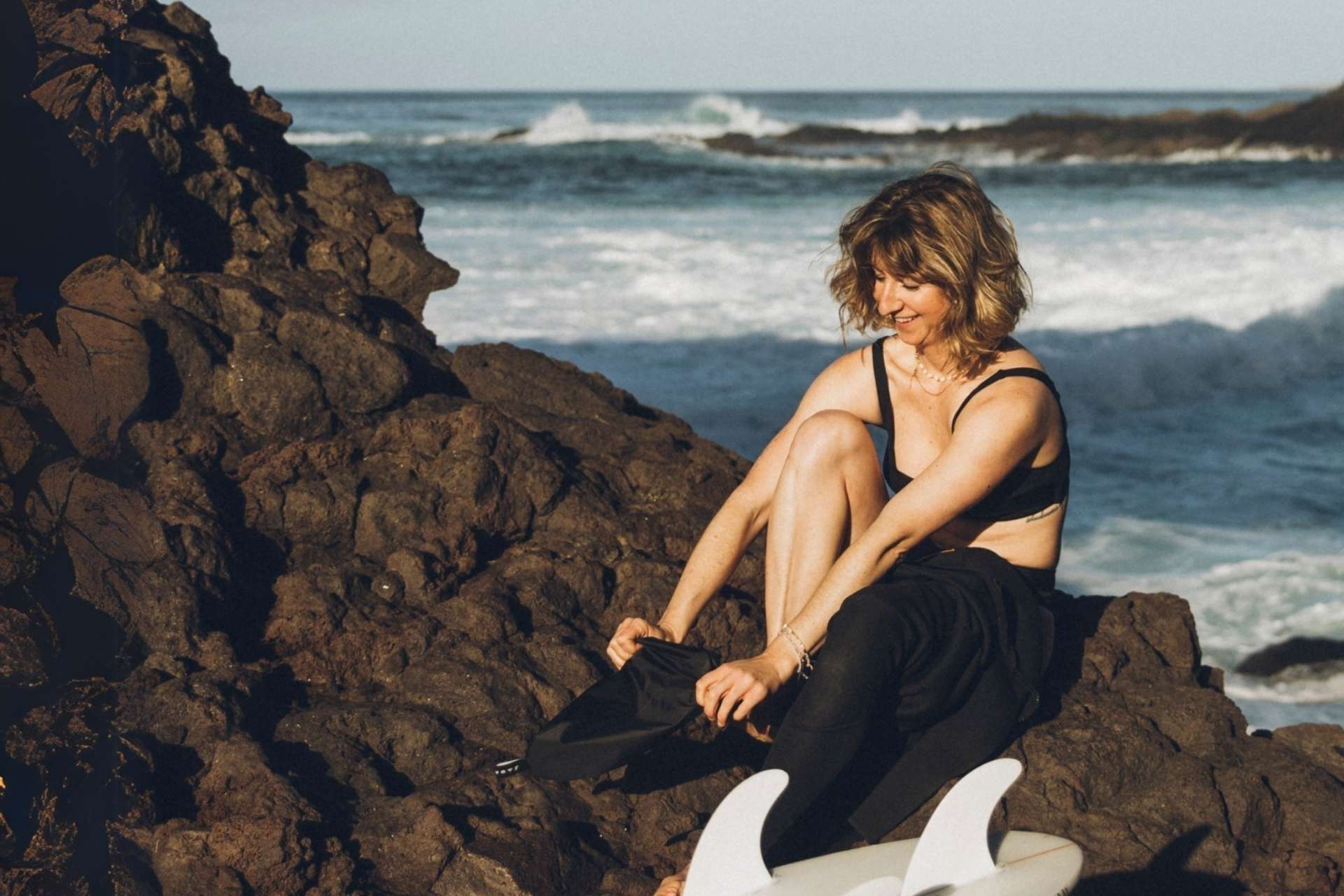 Surferin benutzen Surf Lube Neoprenanzug Anziehhilfe am Meer